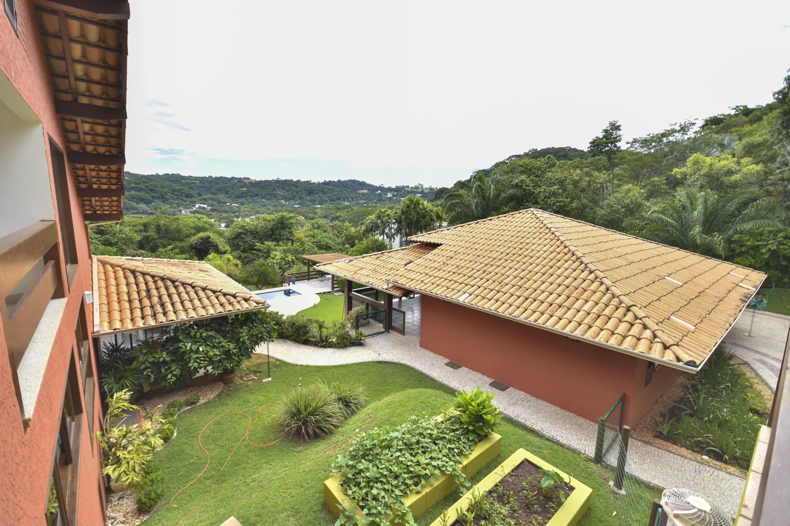 Vista aérea parcial do Residencial Aldeia do Vale mostrando telhados e mata atlântica