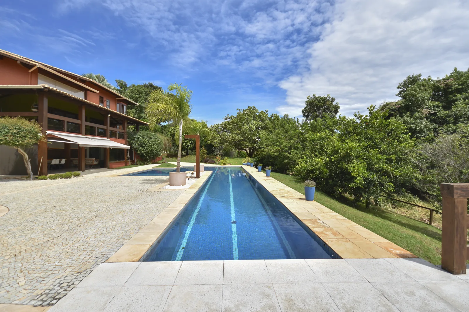 Piscina com raia de 20 metros em close, revestimento em pedra natural