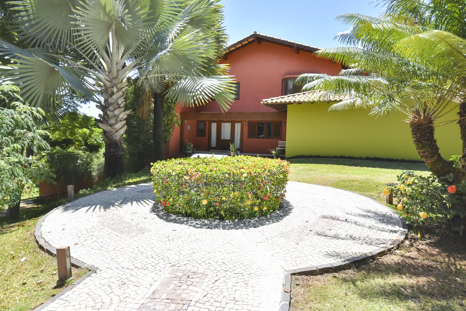 Fachada frontal com rotunda de paralelepípedos e palmeiras reais