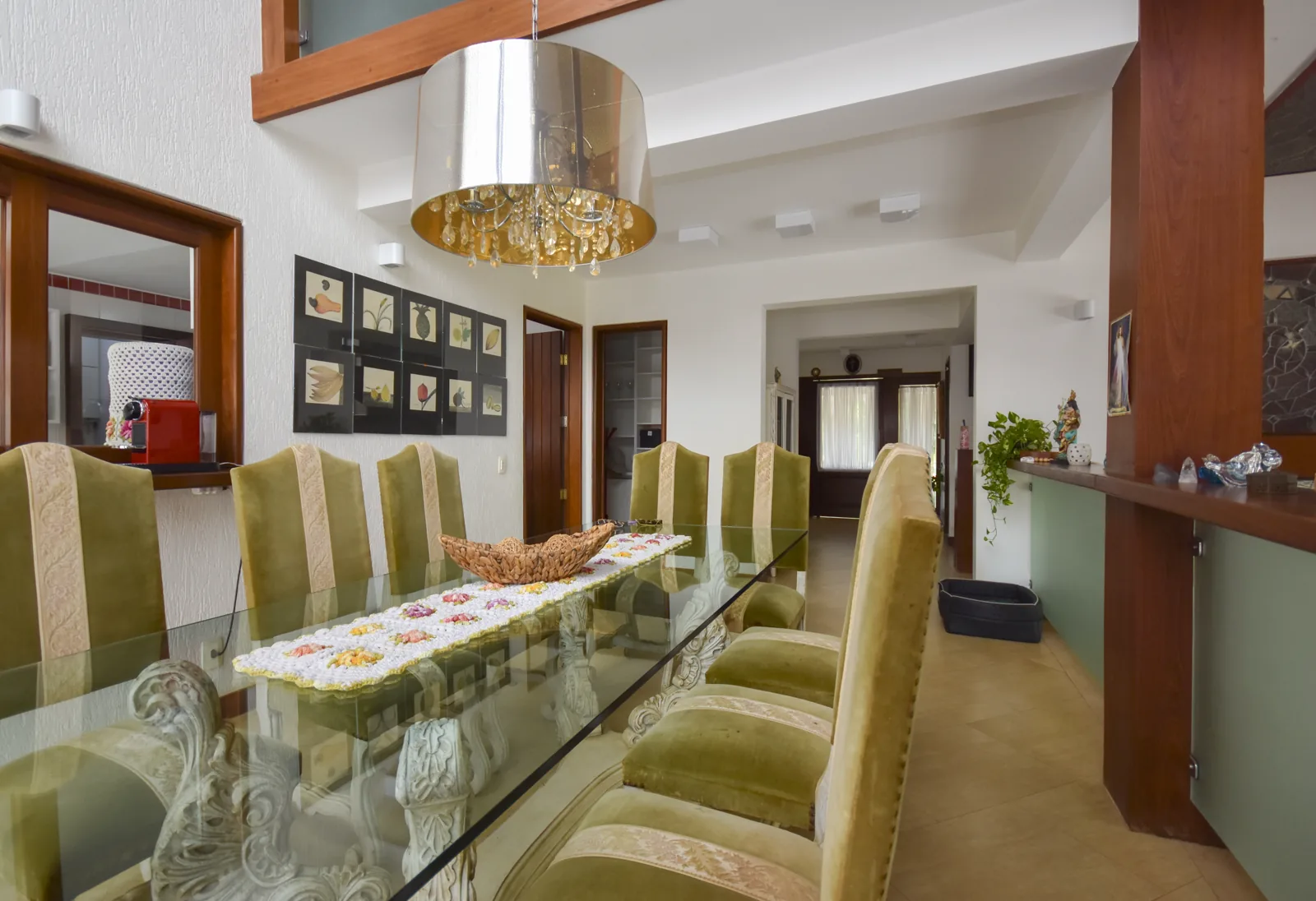 Sala de jantar com mesa de vidro para doze lugares e luminárias em âmbar
